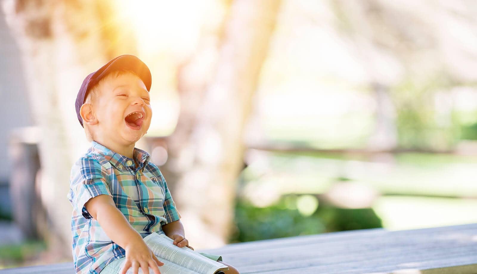 Lachendes Kind auf einer Bank (c) CC0 1.0 - Public Domain (von unsplash.com)