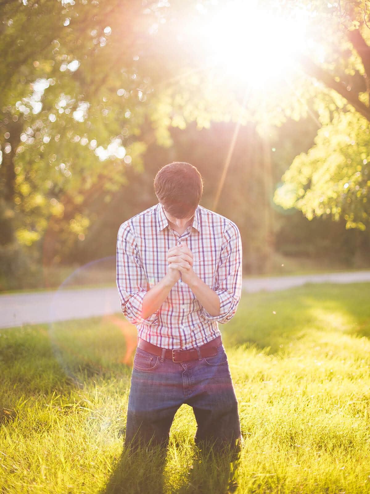 Betender auf einer Wiese, im Hintergrund scheint die Sonne
